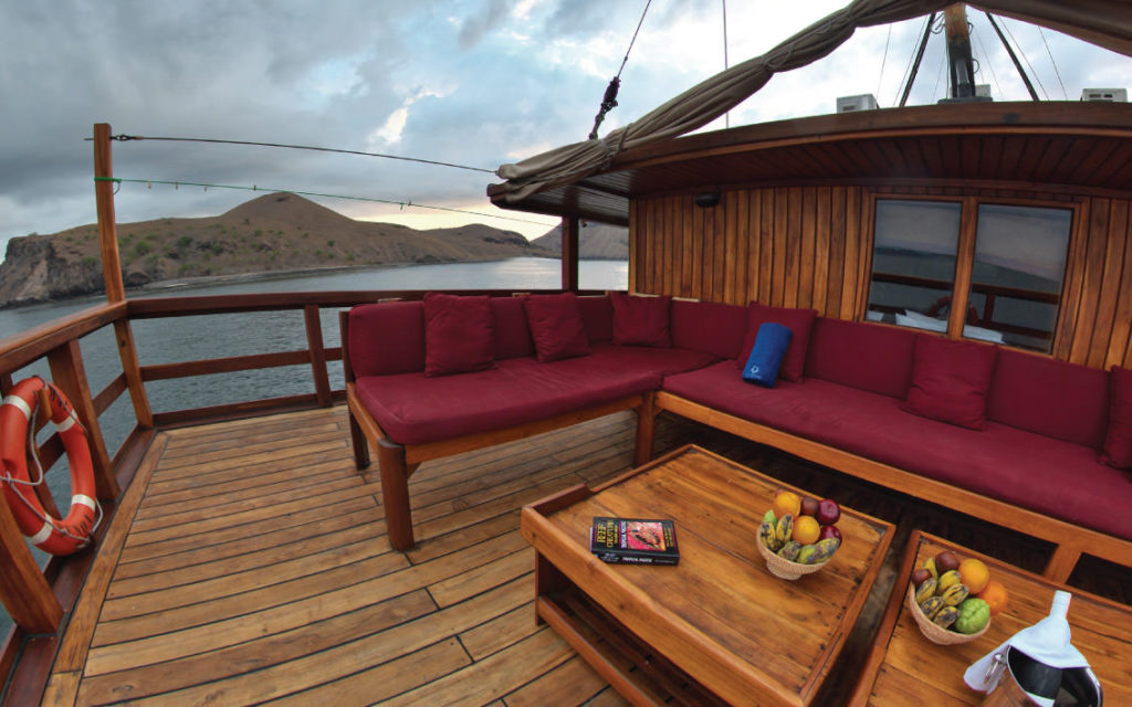Private Boat Labuan Bajo Charter - outdoor relaxing area, long chair and table with fruits and book